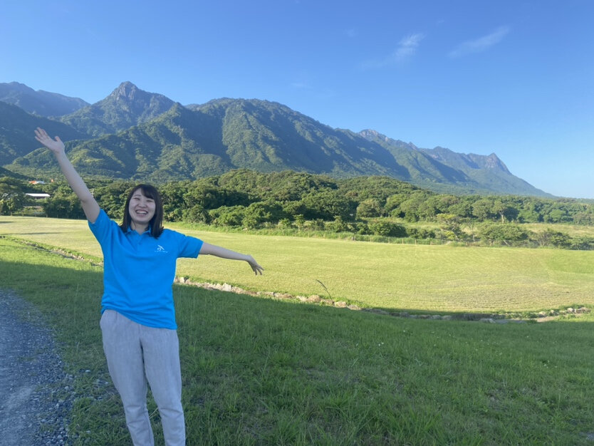 屋久島の景色と半そでの服を着ているスタッフ